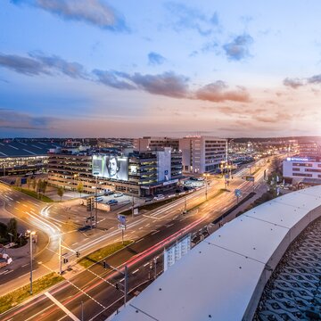 Blick vom Parkhaus des Flughafens Stuttgart auf die Flughafenstraße bei Sonnenuntergang mit moderner Architektur und fließendem Verkehr.