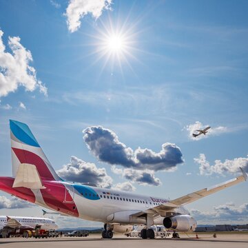 Flugzeuge auf dem Vorfeld des Flughafens Stuttgart bei Sonnenschein und blauem Himmel mit vereinzelten Wolken.